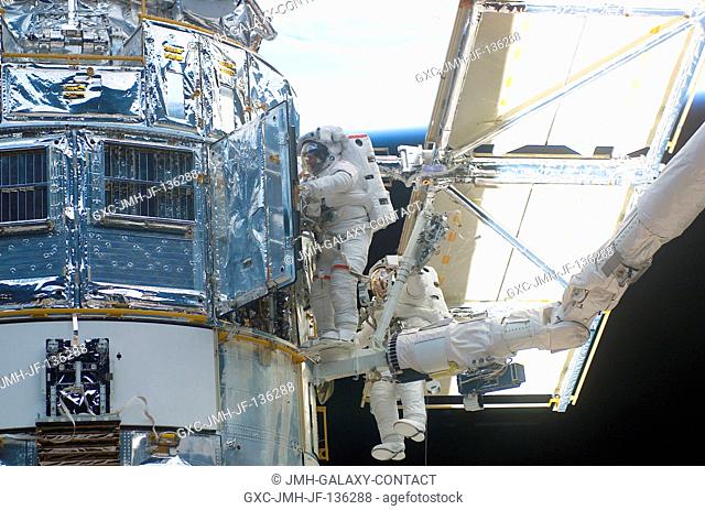 Astronaut John M. Grunsfeld, payload commander, works in tandem with astronaut Richard M. Linnehan, mission specialist, as the two devote their attention to the...