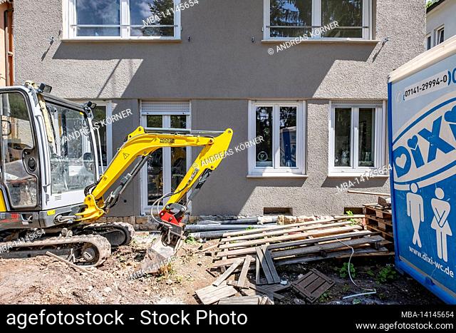 construction site, renovation and renovation of an apartment, small excavator stands in front of a renovated house