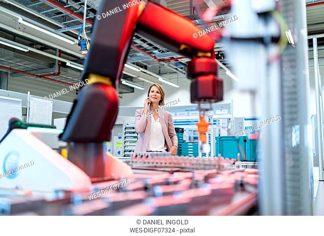 Businesswoman on cell phone in a modern factory hall