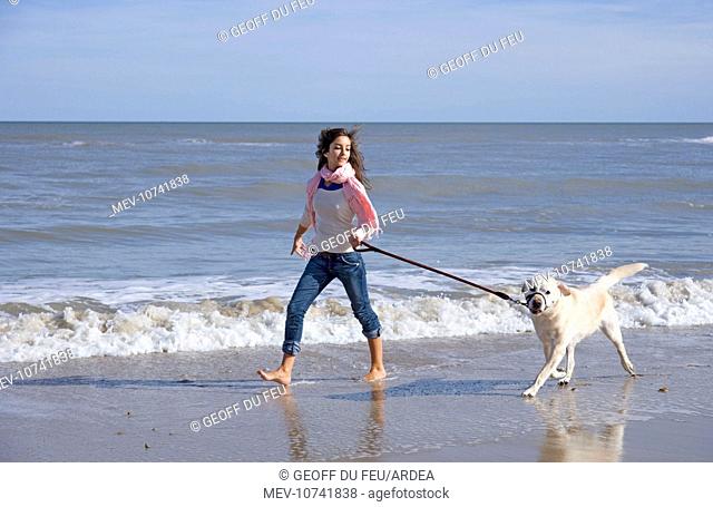 Teenage Girl Walking Labrador Dog on Beach