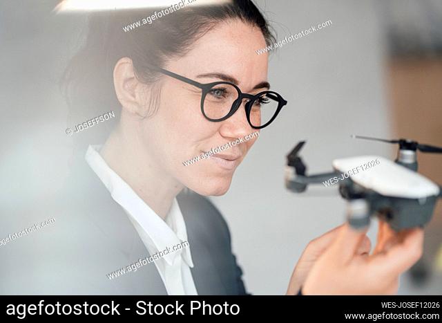 Smiling businesswoman wearing eyeglasses analyzing drone