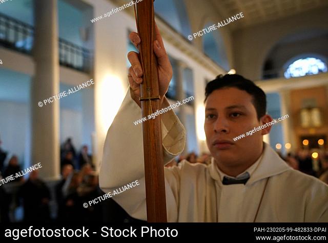 05 February 2023, Schleswig-Holstein, Neumünster: An altar boy carries a small cross at the funeral service for the victims of the knife attack in a regional...