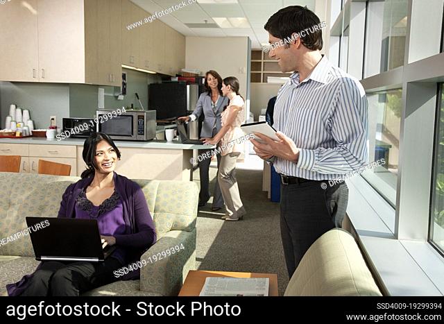 Business colleagues talking to each other standing in office breakroom