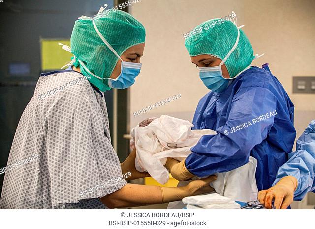 Reportage in the maternity service of Métropole Savoie hospital in Chambéry, France. A planned cesarean delivery. A nurse takes the baby over to its mother