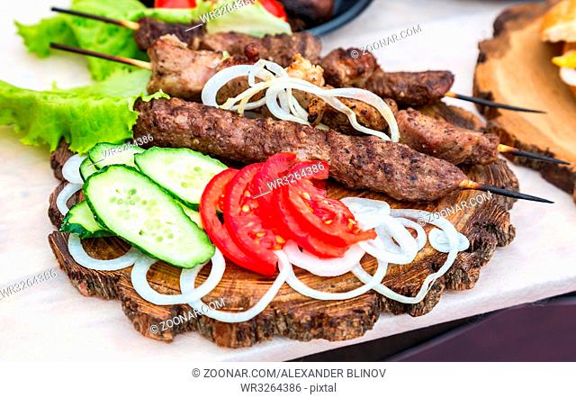 Grilled shish kebab or shashlik on wooden skewers with fresh vegetables