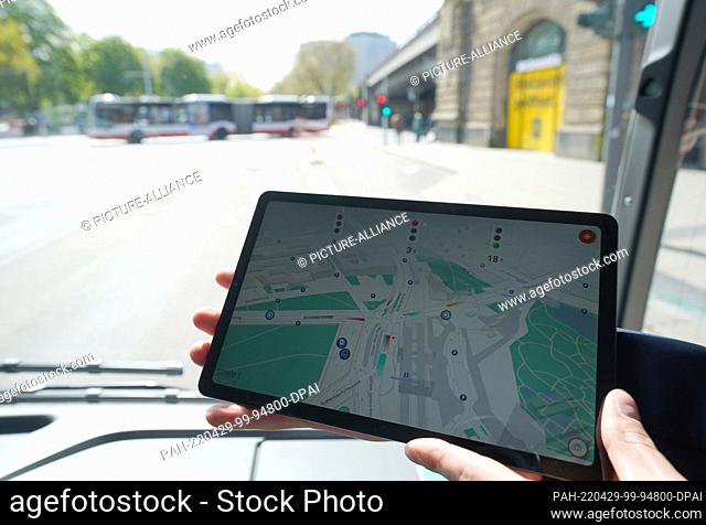29 April 2022, Hamburg: An employee holds a tablet with an information app about the traffic situation on a bus on the test track for automated and connected...