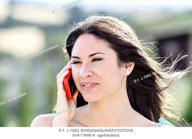 Pretty girl talks with mobile phone in the countryside