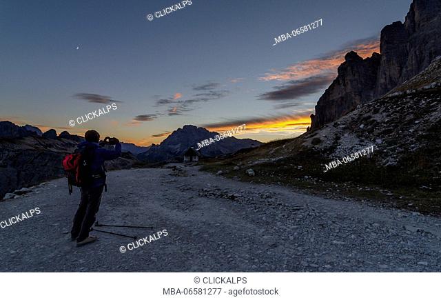 Tre Cime di Lavaredo, Three peaks of lavaredo, Drei Zinnen, Dolomites, Veneto, South Tyrol, Italy, Hiker photographs sunset at Tre Cime di Lavaredo