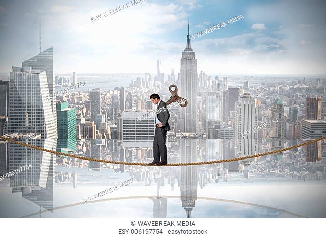 Composite image of wound up businessman with hands on hips on tightrope
