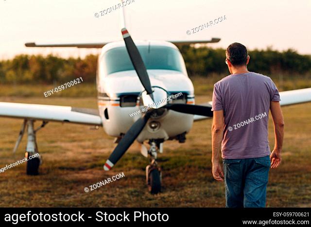 Pilot man walking next to a small private airplane
