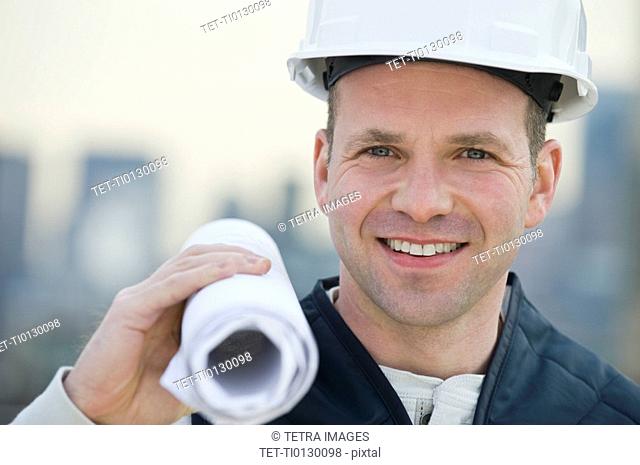 Male construction worker holding blueprints