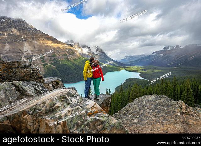 Couple kissing, view of turquoise glacial lake surrounded by forest, Peyto Lake, Rocky Mountains, Banff National Park, Alberta Province, Canada, North America