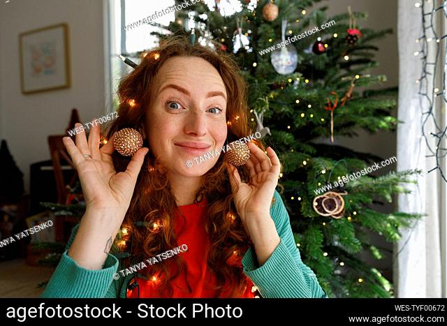 Smiling woman with earrings in front of Christmas tree