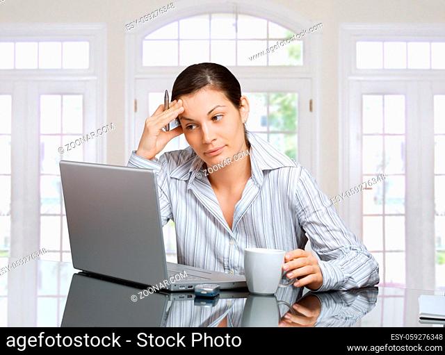 Young woman sits in front of laptop at home and she is thinking how to solve a problem