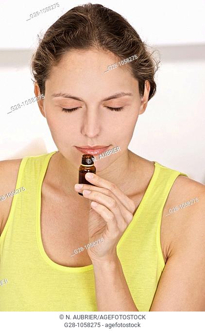 young woman smelling a small bottle of essential oil