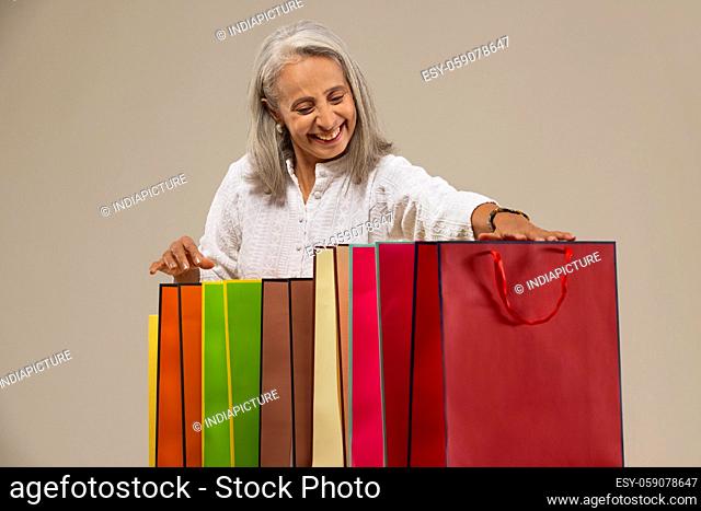 An old woman happily looking at her colorful carrybags