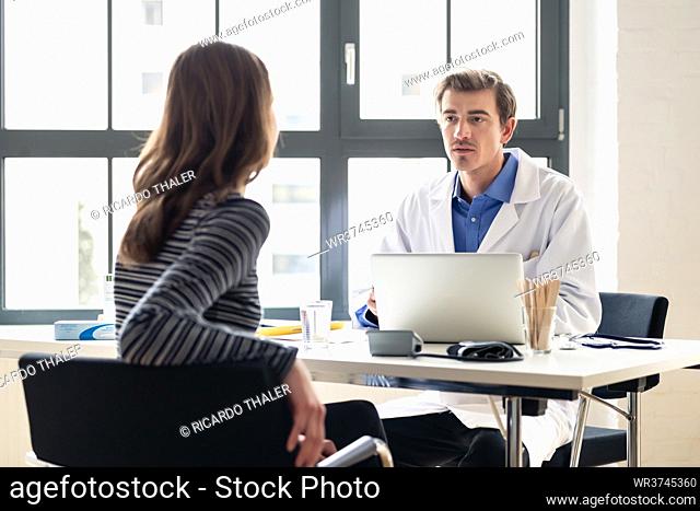 High angle view of a young physician listening to his patient with respect and dedication, during a private consultation in the office of a modern medical...
