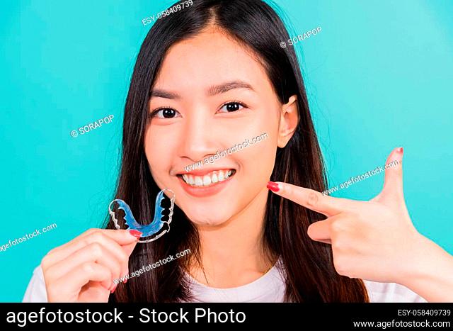 Female hold teeth retaining tools after removable braces, Portrait young Asian beautiful woman smiling pointing with finger silicone orthodontic retainers for...