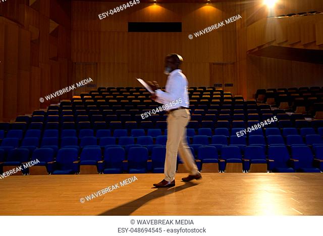 Businessman practicing and learning script while walking in the auditorium