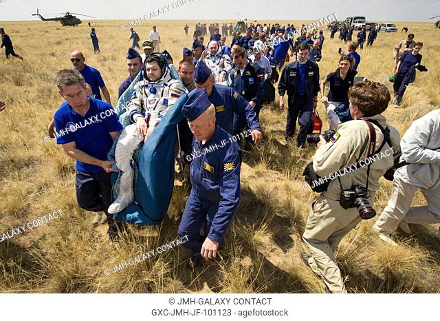 Support and medical personnel carry Expedition 31 Commander Oleg Kononenko of Russia, foreground, and Flight Engineers Andre Kuipers of the European Space...