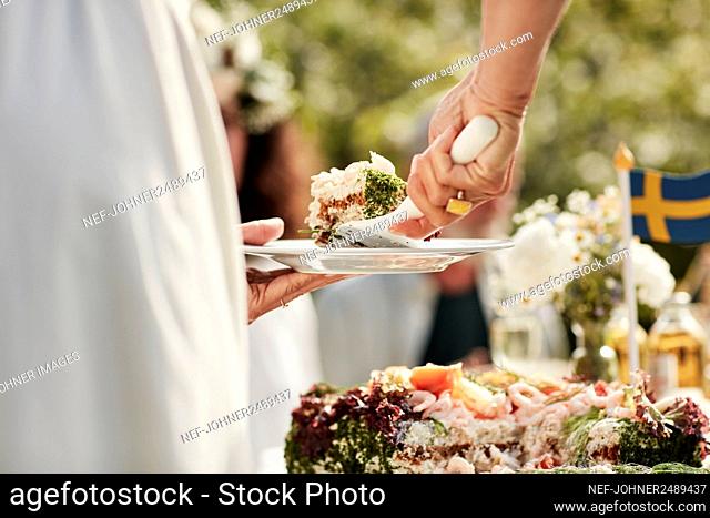 Close-up of woman putting cake on plate