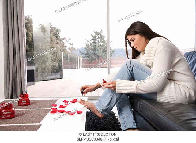 Woman painting toenails in living room