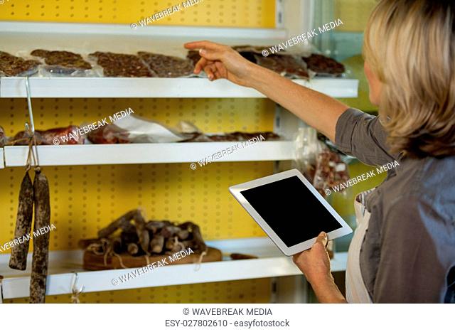 Female staff maintain records of meat on digital tablet at counter