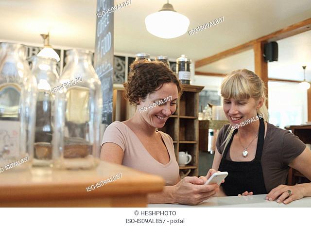 Female shop assistants looking at smartphone in country store