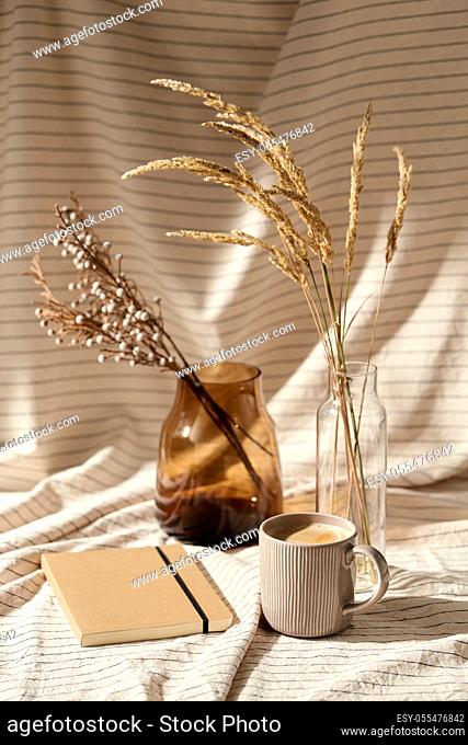 cup of coffee, diary and dried flowers in vases
