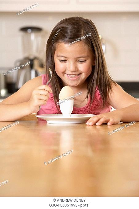 Young girl in kitchen with a boiled egg smiling
