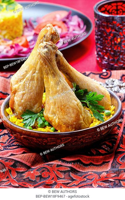 Indian cuisine: roasted chicken with rice and green peas on vivid red background