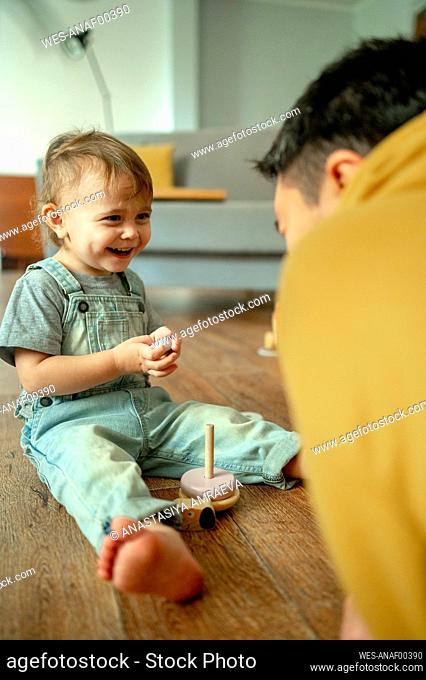 Happy boy and father playing with wooden toys at home