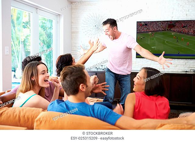Group Of Friends Sitting On Sofa Watching Soccer Together