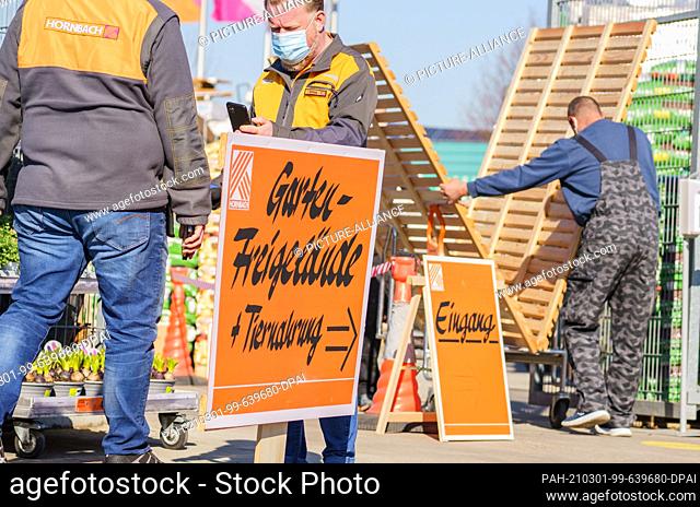 01 March 2021, Rhineland-Palatinate, Mainz: Two employees stand in the entrance area of the Hornbach garden center. On 1 March