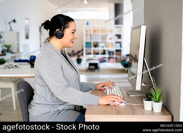 Smiling female freelancer using computer while working at home