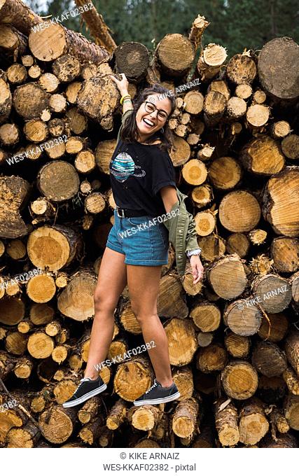 Happy young woman balancing on stack of wood