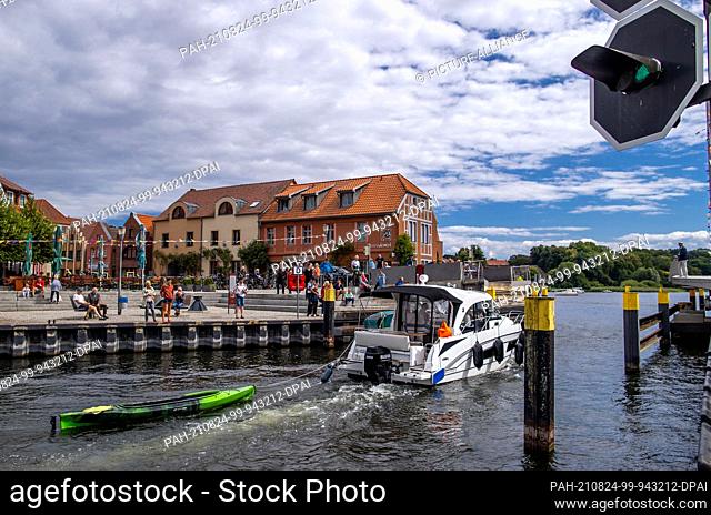 08 August 2021, Mecklenburg-Western Pomerania, Malchow: A motorboat drives through the open swing bridge into Lake Malchow