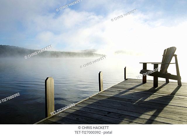 USA, New York, St. Armand, Lake Placid, Outdoor chair on pier by lake
