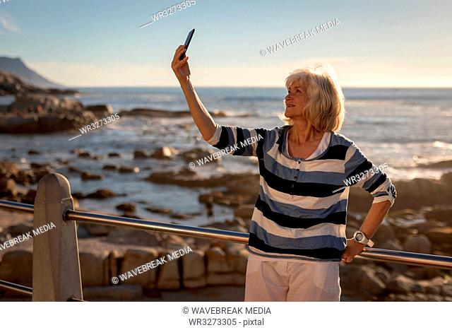 Active senor woman taking selfie with mobile phone on a promenade