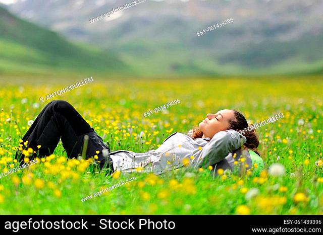 Side view portrait of a hiker resting lying in a green field in the high mountain