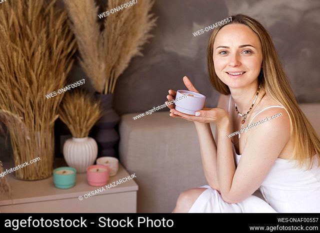 Smiling blond woman holding scented candle