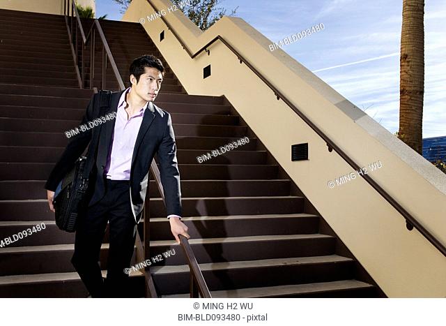 Asian businessman descending staircase