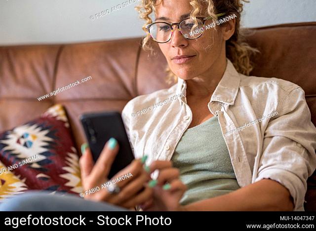 close up of woman using modern smart phone at home sitting on the sofa enjoying internet connection wireless - female people with application on cellular...