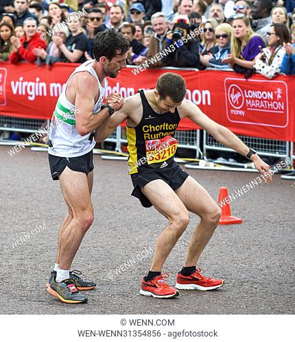 Matthew Rees (left) of Swansea Harriers unselfishly helps David Wyeth of Chorlton Runners reach the finish line during the Virgin Money London Marathon...