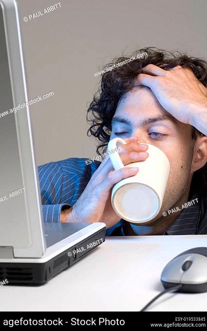 tired man at computer desk with coffee