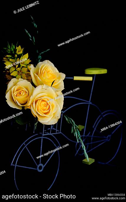 Bicycle with a bouquet of yellow flowers against a black background