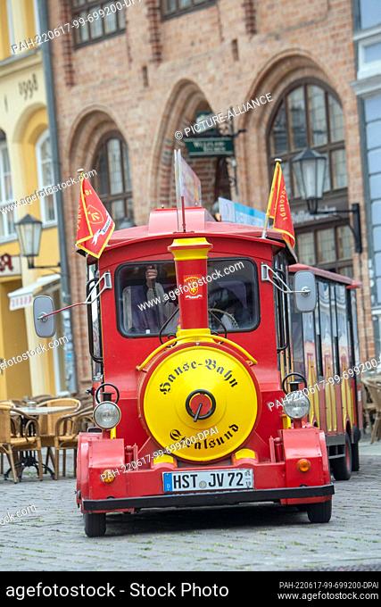 31 May 2022, Mecklenburg-Western Pomerania, Stralsund: Against the backdrop of the medieval Old Market, the red and yellow Hanseatic Railway runs
