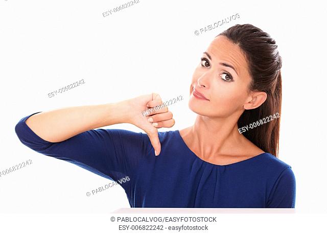 Attractive adult in blue shirt with thumb down, gesturing bad job, while looking at you in white background