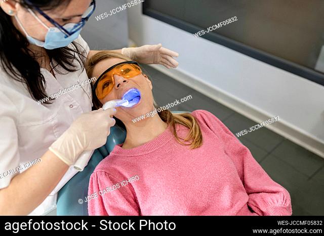Dentist drying dental filling with curing light at dental clinic