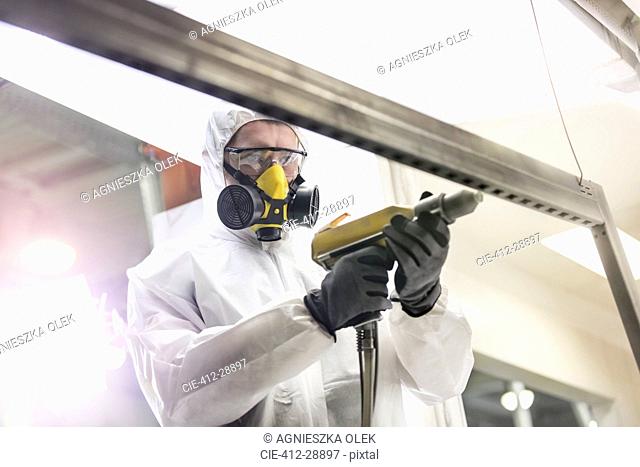 Worker in protective workwear using drill in factory